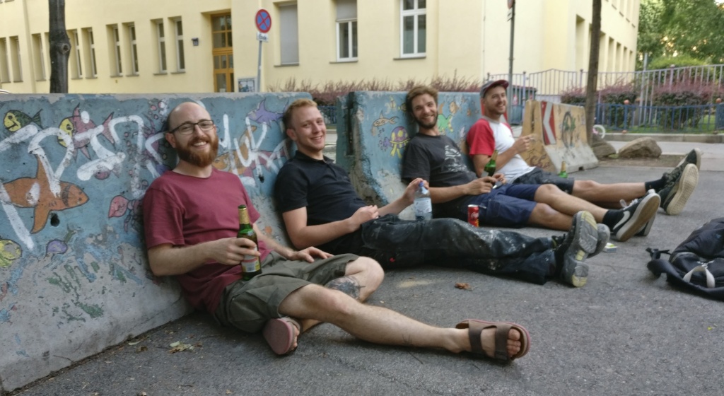 Das Team sitzt auf dem Boden, gegen Straßensperren gelehnt. Von links nach rechts: Christian, Kajetan, Tobi, Felix
